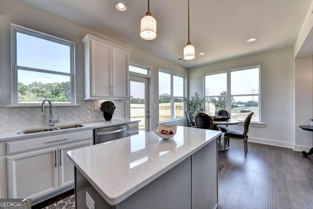 kitchen featuring sink, white cabinetry, decorative light fixtures, stainless steel dishwasher, and light stone countertops