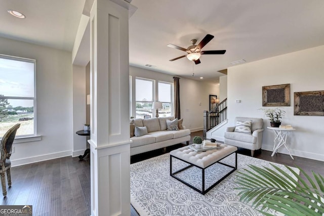 living room featuring decorative columns, dark hardwood / wood-style floors, and ceiling fan