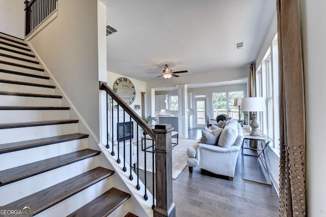 staircase with decorative columns, hardwood / wood-style floors, and ceiling fan