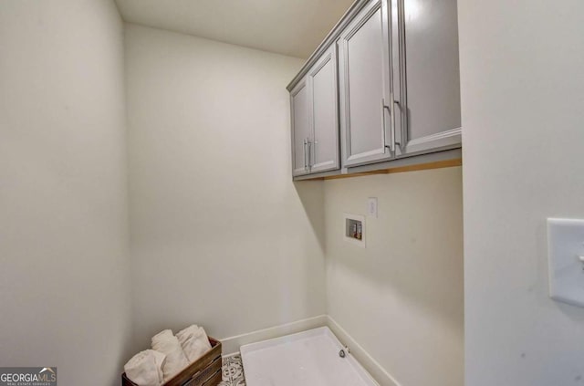 clothes washing area featuring hookup for a washing machine and cabinets