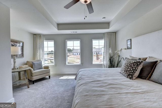 carpeted bedroom with a tray ceiling and ceiling fan