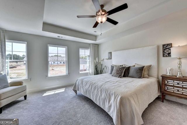 carpeted bedroom with ceiling fan and a tray ceiling