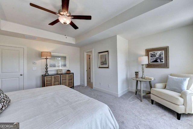 bedroom featuring light colored carpet, a raised ceiling, and ceiling fan