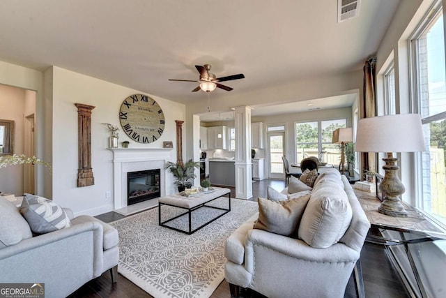 living room featuring ceiling fan, dark hardwood / wood-style floors, and ornate columns