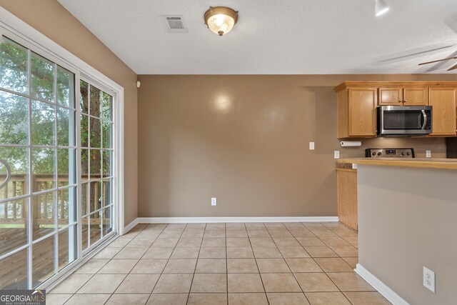 kitchen featuring light tile patterned floors, a textured ceiling, ceiling fan, and range