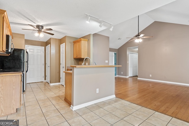 kitchen with light tile patterned flooring, light brown cabinetry, sink, ceiling fan, and kitchen peninsula