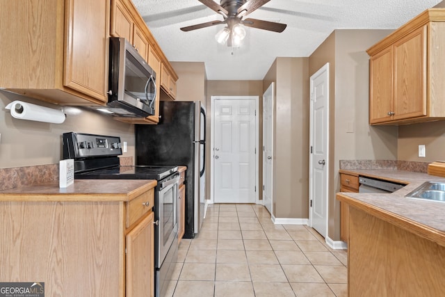 kitchen featuring appliances with stainless steel finishes, light brown cabinetry, light tile patterned floors, ceiling fan, and a textured ceiling