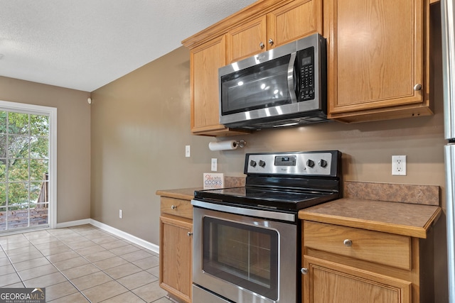 kitchen with light tile patterned floors, a textured ceiling, and appliances with stainless steel finishes