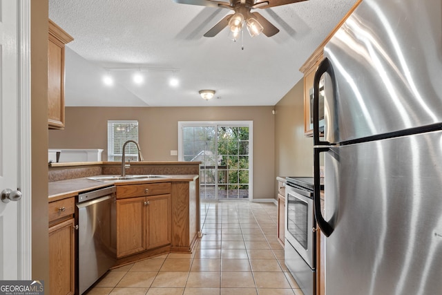 kitchen featuring sink, light tile patterned floors, ceiling fan, stainless steel appliances, and a textured ceiling