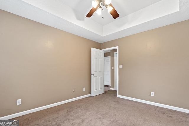 carpeted empty room featuring ceiling fan and a tray ceiling