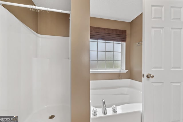 bathroom featuring separate shower and tub and a textured ceiling