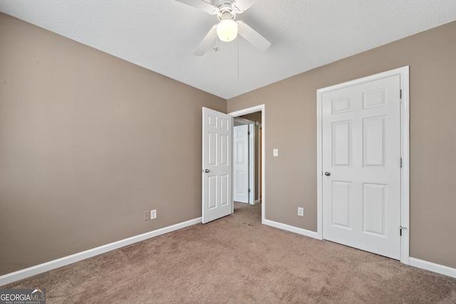 unfurnished bedroom with ceiling fan, light colored carpet, and a textured ceiling