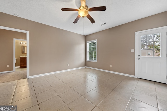 spare room with ceiling fan, plenty of natural light, light tile patterned floors, and a textured ceiling