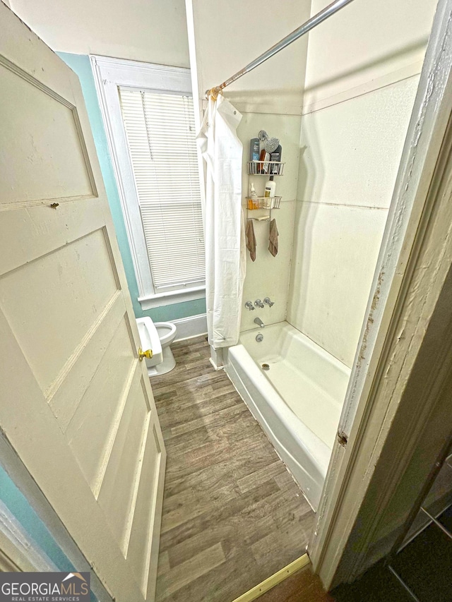 bathroom featuring shower / bath combo, hardwood / wood-style floors, and toilet