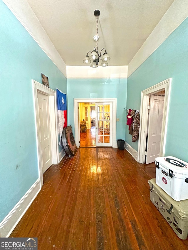 hallway with dark wood-type flooring and an inviting chandelier