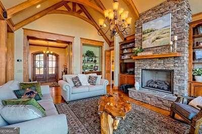 living room featuring french doors, a chandelier, lofted ceiling with beams, built in features, and a fireplace