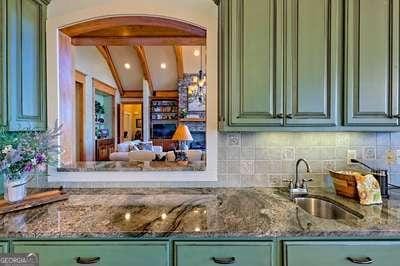 bar featuring sink, decorative backsplash, lofted ceiling with beams, and green cabinets