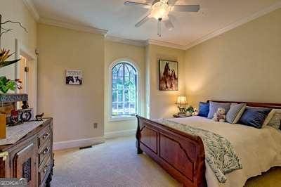 carpeted bedroom with ornamental molding and ceiling fan