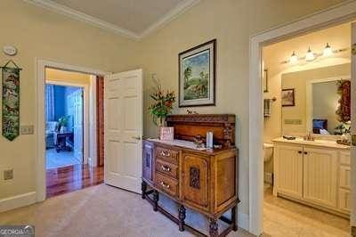 corridor with ornamental molding and light carpet