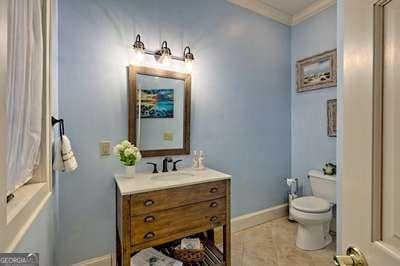 bathroom featuring tile patterned flooring, vanity, crown molding, and toilet