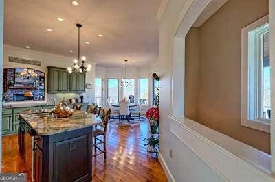 kitchen with dark hardwood / wood-style flooring, a kitchen island, a notable chandelier, pendant lighting, and light stone countertops