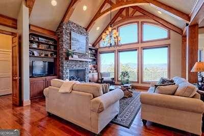 living room featuring high vaulted ceiling, dark hardwood / wood-style floors, built in features, and a chandelier