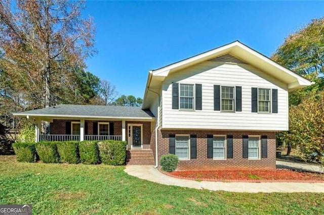 split level home with brick siding, covered porch, and a front yard