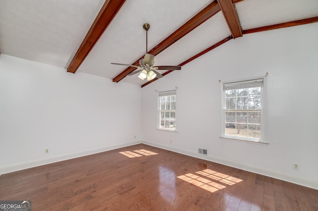 unfurnished room with visible vents, wood-type flooring, baseboards, and vaulted ceiling with beams