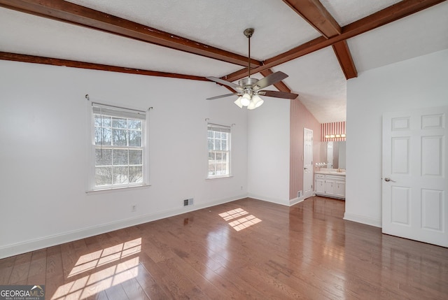 interior space with baseboards, wood-type flooring, ceiling fan, and vaulted ceiling with beams