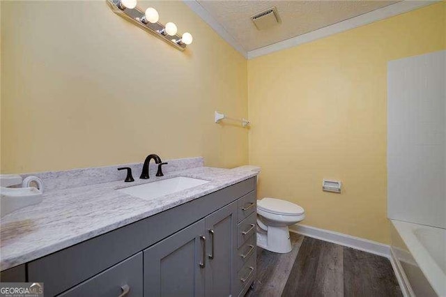 full bathroom featuring visible vents, toilet, vanity, ornamental molding, and a textured ceiling