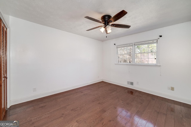 spare room featuring baseboards, dark wood-style floors, visible vents, and ceiling fan