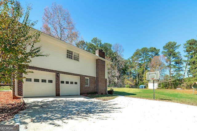 view of side of home with a chimney, concrete driveway, a garage, a lawn, and brick siding