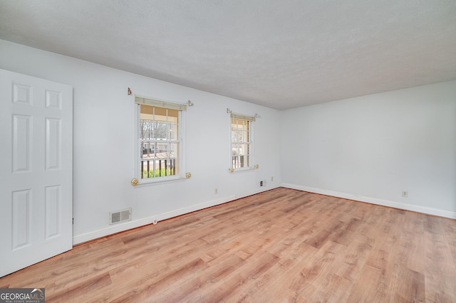 empty room featuring baseboards, a textured ceiling, and wood finished floors