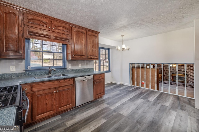 kitchen featuring an inviting chandelier, dark wood-style flooring, a sink, stainless steel appliances, and dark countertops