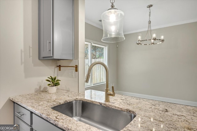 kitchen featuring pendant lighting, sink, gray cabinetry, light stone counters, and crown molding