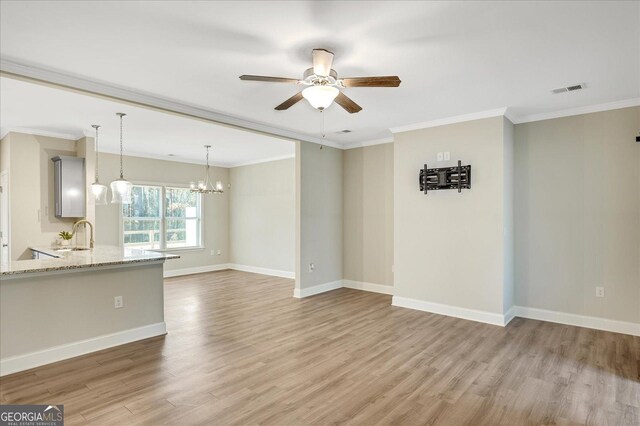 unfurnished living room featuring crown molding, wood-type flooring, sink, and ceiling fan with notable chandelier