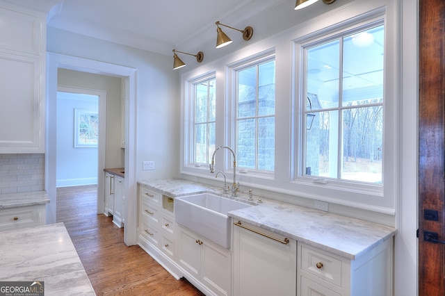 kitchen with sink, light stone countertops, and white cabinets