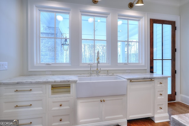 kitchen featuring white cabinetry, sink, and light stone counters