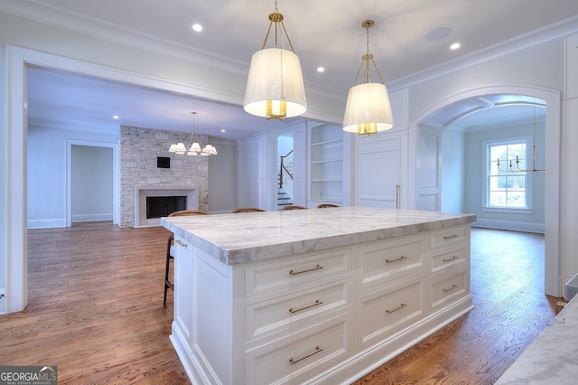 kitchen featuring hanging light fixtures, a kitchen breakfast bar, ornamental molding, white cabinets, and a kitchen island