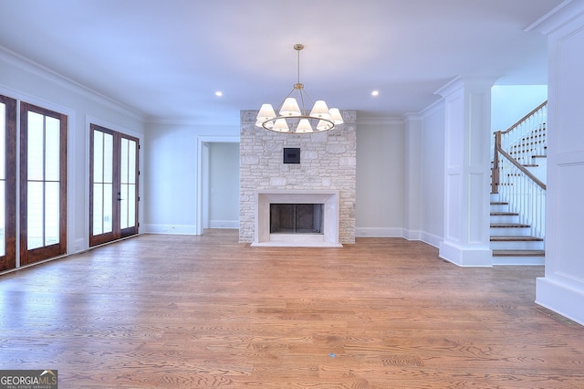 unfurnished living room featuring crown molding, a fireplace, an inviting chandelier, and hardwood / wood-style flooring