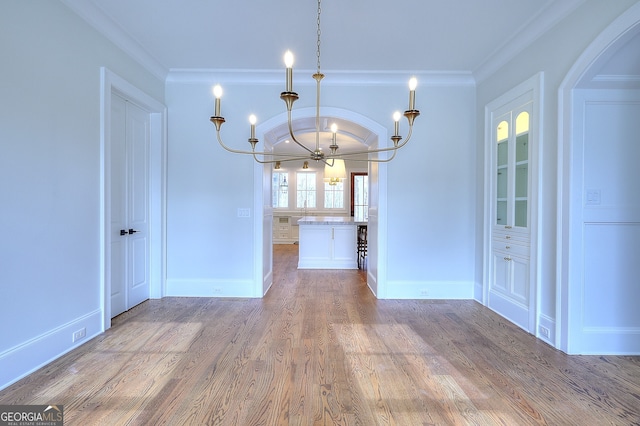 unfurnished dining area featuring ornamental molding, hardwood / wood-style floors, and a notable chandelier