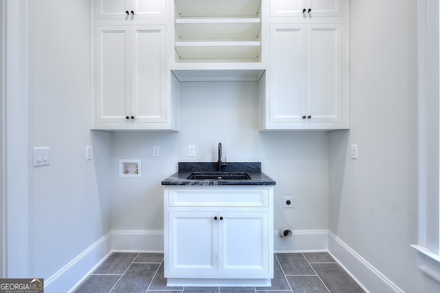 laundry room featuring electric dryer hookup, sink, hookup for a washing machine, and dark tile patterned floors