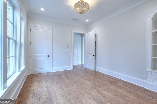 unfurnished bedroom with multiple windows, ornamental molding, and light hardwood / wood-style flooring