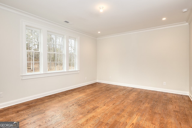 spare room with ornamental molding and light wood-type flooring