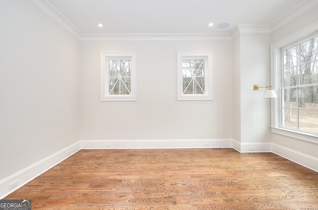 empty room with crown molding, plenty of natural light, and hardwood / wood-style floors