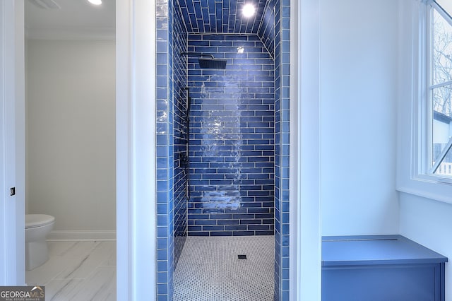 bathroom with ornamental molding, a healthy amount of sunlight, toilet, and a tile shower