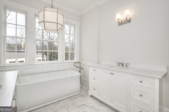 bathroom with vanity, crown molding, and a tub