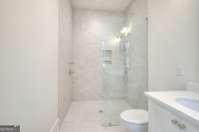 bathroom featuring tiled shower, vanity, and toilet