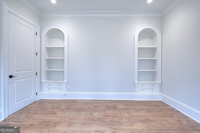 unfurnished room featuring crown molding, hardwood / wood-style floors, and built in shelves