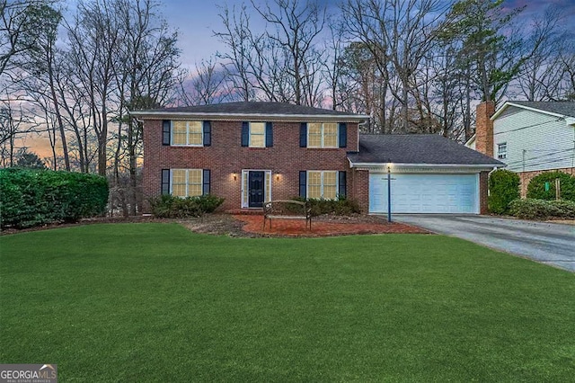 colonial-style house featuring a garage, driveway, a front lawn, and brick siding